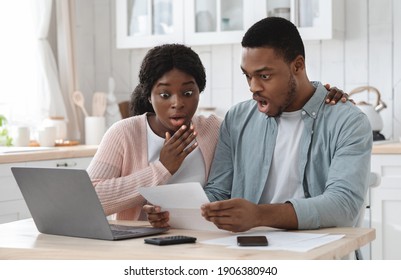 Shocked black couple in kitchen stressed with financial problems, doing calculations of family budget together. Frustrated african american spouses sitting at table looking at loan documents