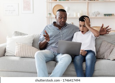 Shocked Black Grandad And His Preteen Grandson Watching Scary Movie On Laptop, Sitting At Home With Dazed Face Expressions, Copy Space