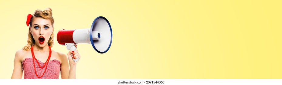 Shocked Blond Woman Holding Mega Phone And Shout Something. Girl In Red Pin Up Style With Wide Open Mouth, On Light Yellow Background With Copy Space. Female Model In Retro Vintage Studio Ad Concept.