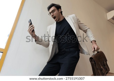 Shocked businessman checking smartphone while walking downstairs