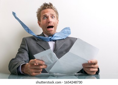 Shocked Businessman Opening A Letter With A Wide-eyed Gasp Of Surprise