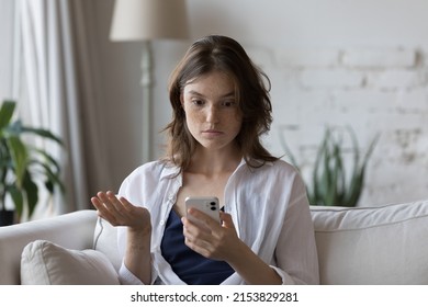 Shocked concerned cellphone user girl staring at screen, looking at smartphone screen, finding problems with online app, poor connection, Internet service, getting surprising bad news