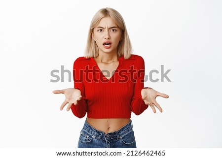 Shocked and confused blond modern girl shrugging, looking puzzled, cant understand whats wrong, what happened, standing questioned against white background