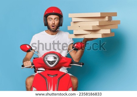 Shocked delivery man in red helmet and white t-shirt riding scooter with pizza boxes on blue background