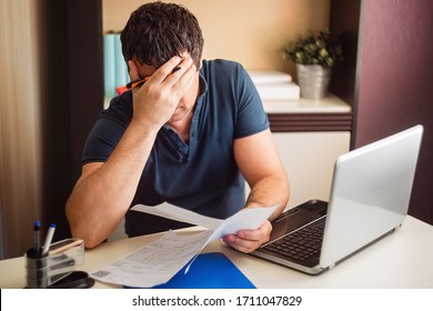 The shocked and disappointed man saw the bad news in the invoices. Frustrated unemployed man with documents. 