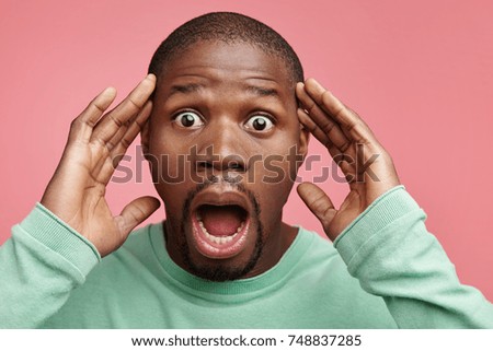 Shocked dismayed dark skinned man keeps mouth opened, gestures actively, stares at camera, being appalled to observe street robbery, can`t call police as is in stupor. Unexcpected events and feelings