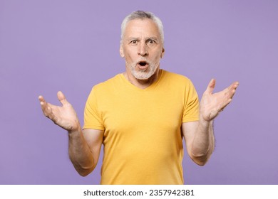 Shocked elderly gray-haired mustache bearded man in yellow t-shirt posing isolated on pastel violet background. People lifestyle concept. Mock up copy space. Keeping mouth open, spreading hands - Powered by Shutterstock