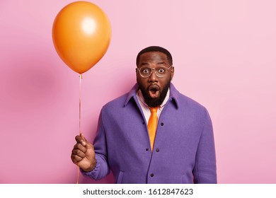 Shocked Embarrassed Man Realizes There Are No Guests On Party, Comes To Congratulate Friend With Anniversary, Wears Elegant Clothes, Stands With Inflated Balloon, Keeps Mouth Opened From Wonder