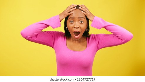Shocked and excited young woman puts hands to head, yellow studio background - Shutterstock ID 2364727717