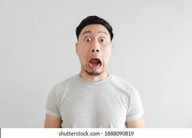 Shocked Face Of Asian Man In Grey T-shirt And Grey Background.