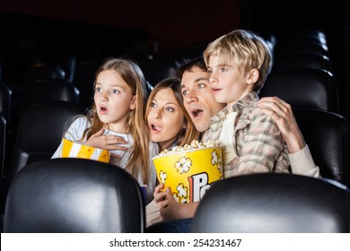 Shocked Family Of Four With Popcorn Watching Movie In Cinema Theater