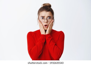 Shocked Female CEO Manager Looking Concerned And Worried, Holding Hands On Face And Staring Scared At Camera, Wearing Glasses, White Background