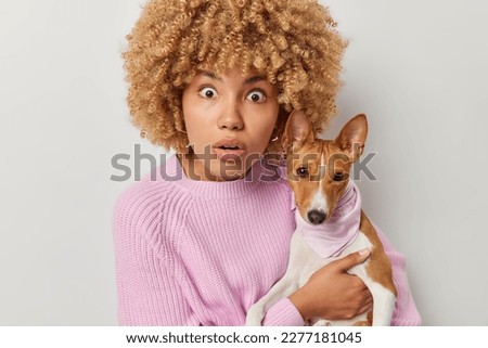 Shocked female pet owner stares at camera with omg expression poses with breed dog cannot believe own eyes dressed in knitted jumper isolated over white background. Domestic animals and friendship