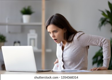 Shocked female sitting at desk looking at laptop screen rounding eyes surprised bad online news, stressed horrified frightened woman in panic with scared face, big trouble, unexpected results concept - Shutterstock ID 1354368314