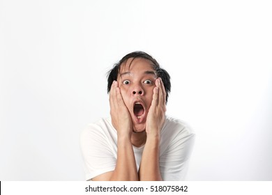 a shocked, funny face man isolated in white background. The man in white T-shirt hold his cheek and looks so surprise. Surprise face, emotion face. 