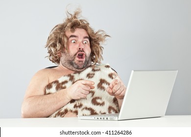 shocked funny prehistoric man using laptop
