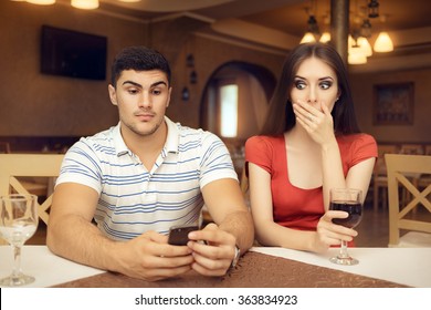 Shocked Girl Spying Boyfriend on Smartphone - Secretive couple having a bad date in a restaurant
