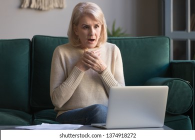 Shocked grey haired mature woman with wide opened eyes reading unexpected online news on laptop, sitting on couch, looking at screen, stressed middle aged female receiving bad email, computer problem - Powered by Shutterstock