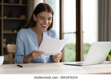 Shocked happy student girl receiving admission letter from university, college, holding, reading paper document at laptop, smiling, laughing, shouting for joy, feeling excited, surprised. Good news