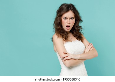 Shocked irritated bride young woman 20s in beautiful white wedding dress holding hands crossed isolated on blue turquoise color wall background studio portrait. Ceremony celebration party concept