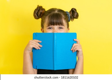 Shocked Kid Girl Covering Face With Book, Hiding Behind It With Eyes Wide Open. Primary School, Reading Book