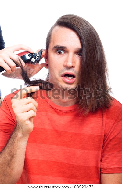 Shocked long haired man being shaved with\
hair trimmer, isolated on white\
background.