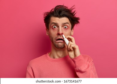 Shocked Man Has Red Swollen Eyes, Splashes Nose Drops, Cures Allergic Rhinitis, Has Home Treatment, Stares At Camera, Poses Against Pink Background Drips Medication Inside. Symptoms Of Cold Or Allergy