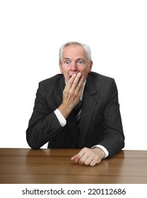 Shocked man sits at table covering her mouth by hand isolated on white background