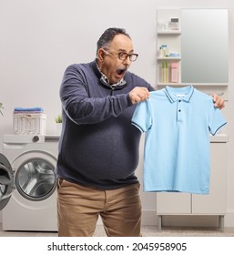 Shocked Mature Man Holding A Shrunken T-shirt In A Bathroom