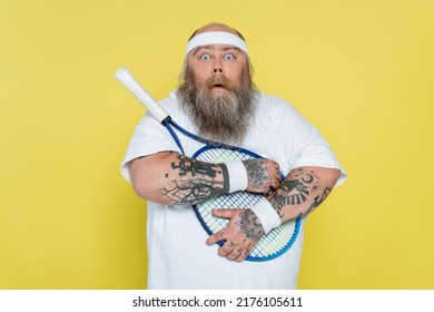 Shocked Overweight Man Hugging Tennis Racquet And Looking At Camera Isolated On Yellow