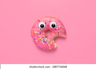 Shocked partially eaten pink donut doughnut on a matching pink background with googly eyes and copy space and room for text. - Powered by Shutterstock