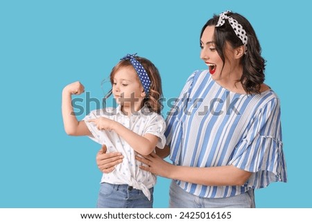 Shocked pin-up woman and her daughter showing muscles on blue background