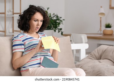 Shocked Pregnant Woman Opening Envelope On Couch At Home