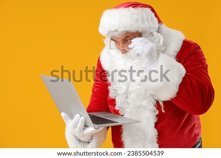 Shocked Santa Claus with laptop on yellow background