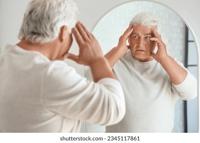 Shocked senior man looking in mirror at home - Powered by Shutterstock