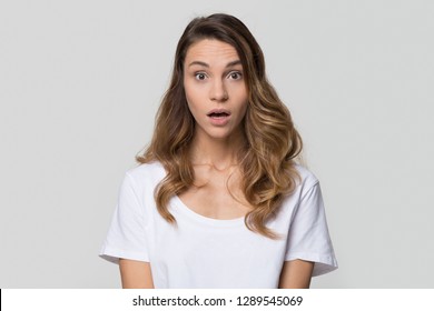 Shocked stunned young woman feeling astonished looking at camera isolated on white studio wall, clueless startled lady with surprised face expression wondering on light blank background, portrait