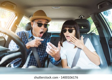 Shocked And Surprised Asian Couple Looking Smartphone In His Car.