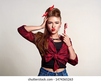 Shocked And Surprised Attractive Girl Smiling Looking To The Side Presenting Your Product . Curly Hair Woman Amazed .Beautiful Girl With Red Candy. Expressive Facial Expressions ,red Lips.Pin Up