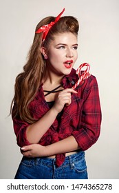 Shocked And Surprised Attractive Girl Smiling Looking To The Side Presenting Your Product . Curly Hair Woman Amazed .Beautiful Girl With Red Candy. Expressive Facial Expressions ,red Lips.Pin Up