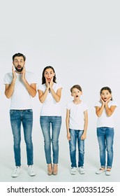 Shocked And Surprised Beautiful Family In T-shirts Standing In Line Looking On Camera Isolated On White Background