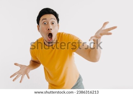 Shocked and surprised face of asian man jumping out isolated on white.