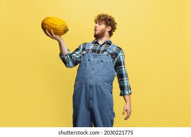 Shocked, Surprised. Funny Bearded Man, Farmer With Big Melon Standing Isolated Over Yellow Studio Background. Concept Of Professional Occupation, Work, Job, Organic Food. Copyspace For Ad, Text.