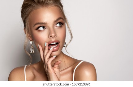 Shocked and surprised girl screaming and  looking to the side presenting  your product . Woman in big earrings and hairstyle amazed . Expressive facial expressions