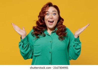 Shocked Surprised Smiling Happy Young Ginger Chubby Overweight Woman 20s Years Old Wears Green Spreading Hands Isolated On Plain Yellow Background Studio Portrait. People Emotions Lifestyle Concept