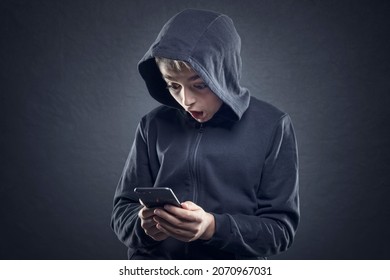 Shocked and surprised teenage boy on the internet with mobile phone concept for amazement, astonishment, making a mistake, stunned and speechless or seeing something he shouldn't see