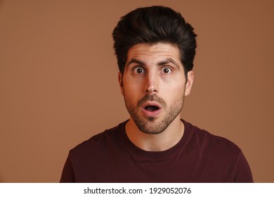 Shocked Unshaven Young Man Expressing Surprise On Camera Isolated Over Beige Background