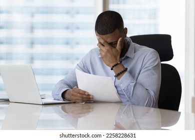 Shocked upset business man reading legal document, getting bad news from sales report, facing problems, bankruptcy, financial loss, bank rejection, touching head, feeling headache, stress, tired - Shutterstock ID 2258228631
