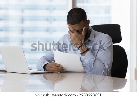 Shocked upset business man reading legal document, getting bad news from sales report, facing problems, bankruptcy, financial loss, bank rejection, touching head, feeling headache, stress, tired