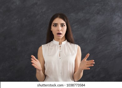 Shocked woman with arms up in air in full disbelief. Surprised girl portrait, dark background. Omg, wtf, human emotions concept