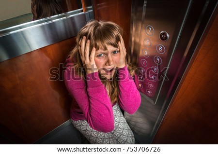 Shocked woman with claustrophobia in the moving modern elevator